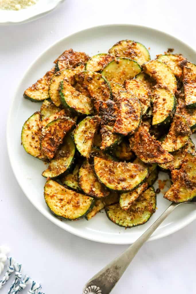 Air fryer sliced and roasted zucchini on a white dinner plate. 