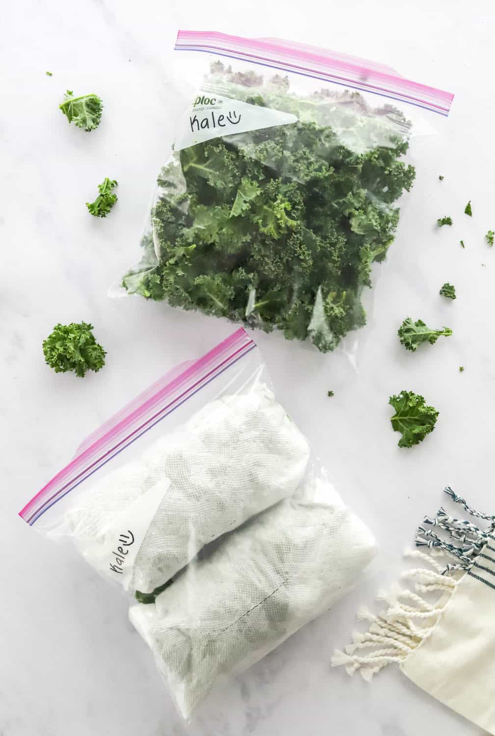 Two freezer bags filled with kale with kale wrapped in paper towels in one of the bags. 