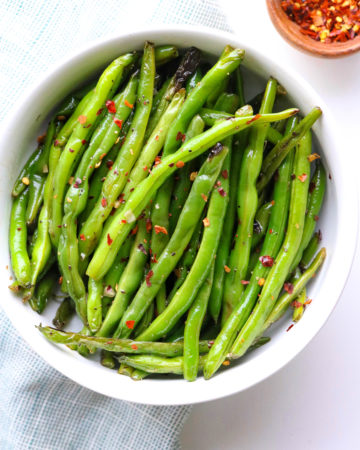 Super Easy Green Beans in a bowl topped with red pepper flakes