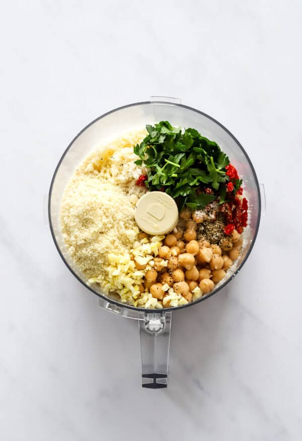 Cauliflower rice, chickpeas and herbs in a food processor before being blended.