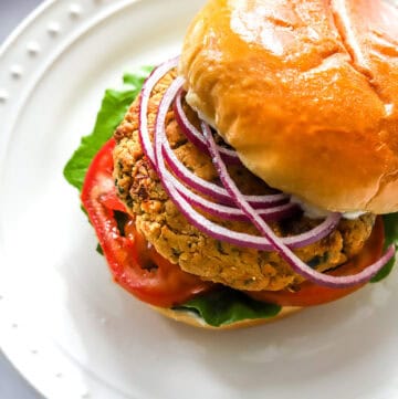 Chickpea cauliflower burger on a bun with lettuce tomato and onion.
