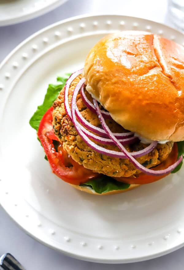 Chickpea cauliflower burger on a bun with lettuce tomato and onion.