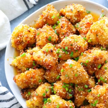 plate of sweet and spicy baked cauliflower wings toppe with diced chives and sesame seeds