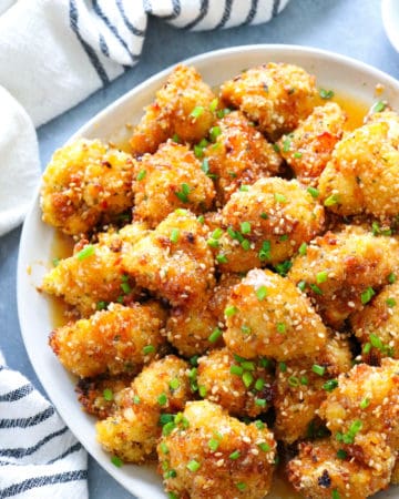 plate of sweet and spicy baked cauliflower wings toppe with diced chives and sesame seeds