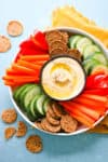platter of classic homemade hummus with carrots and other veggies plus crackers around it
