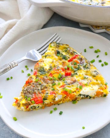 veggie frittata slie on a plate with a silver fork next to it