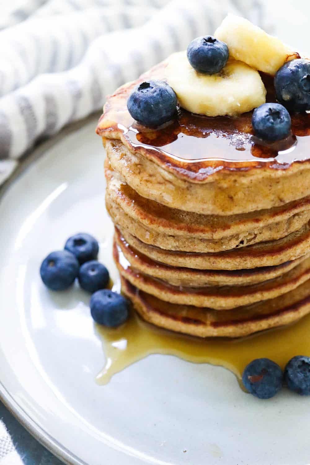 https://pinchmegood.com/wp-content/uploads/2020/08/Pile-of-pancakes-topped-with-syrup-on-a-gray-plate-with-fruit-on-it-scaled.jpg