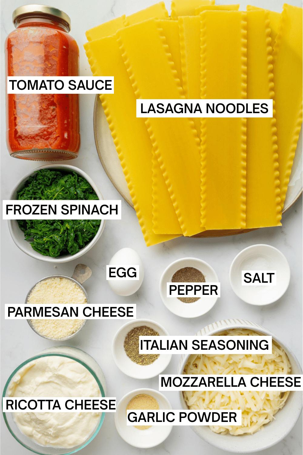 Ingredients for spinach lasagna in bowls with labels over each ingredient. 