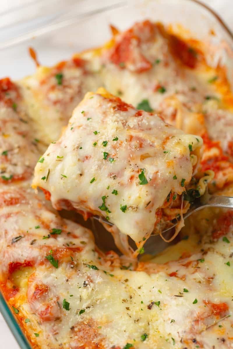 Spatula lifting a lasagna roll up out of a pan. 