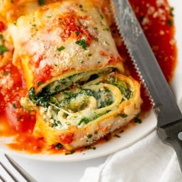 Cut lasagna roll ups with spinach filling on a plate in red sauce.