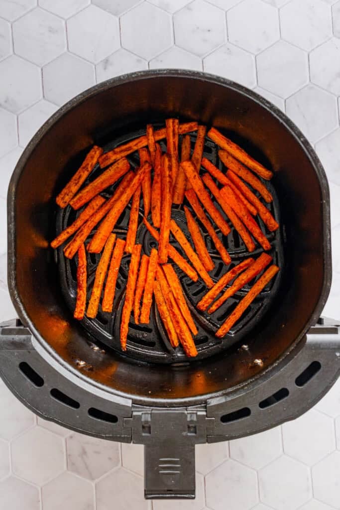 Cooked air fries carrot fries in an air fryer basket.