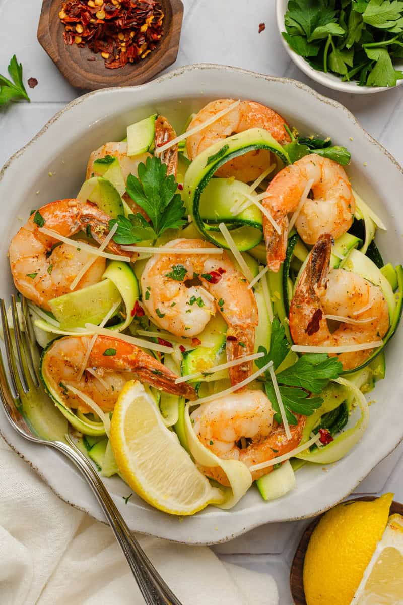 Healthy zucchini noodle scampi shrimp in a bowl with a fork in the bowl with it. 