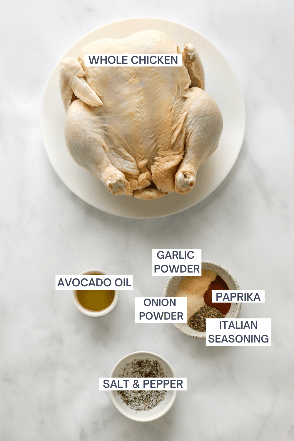 Whole uncooked chicken with a small bowl of oil, a bowl of spices, and a bowl of salt and pepper in front of it. 