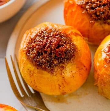 Sweet filled air fryer baked apple on a plate with a fork on the plate with it.