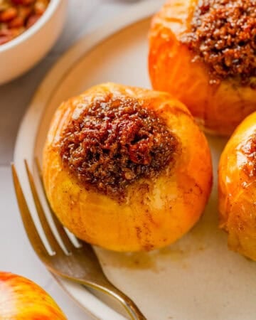 Sweet filled air fryer baked apple on a plate with a fork on the plate with it.