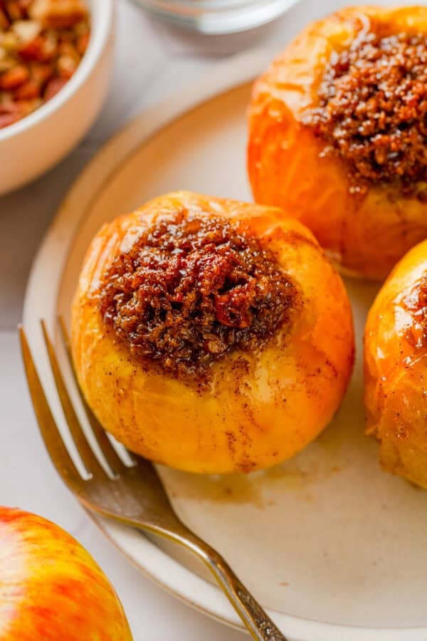 Sweet filled air fryer baked apple on a plate with a fork on the plate with it.