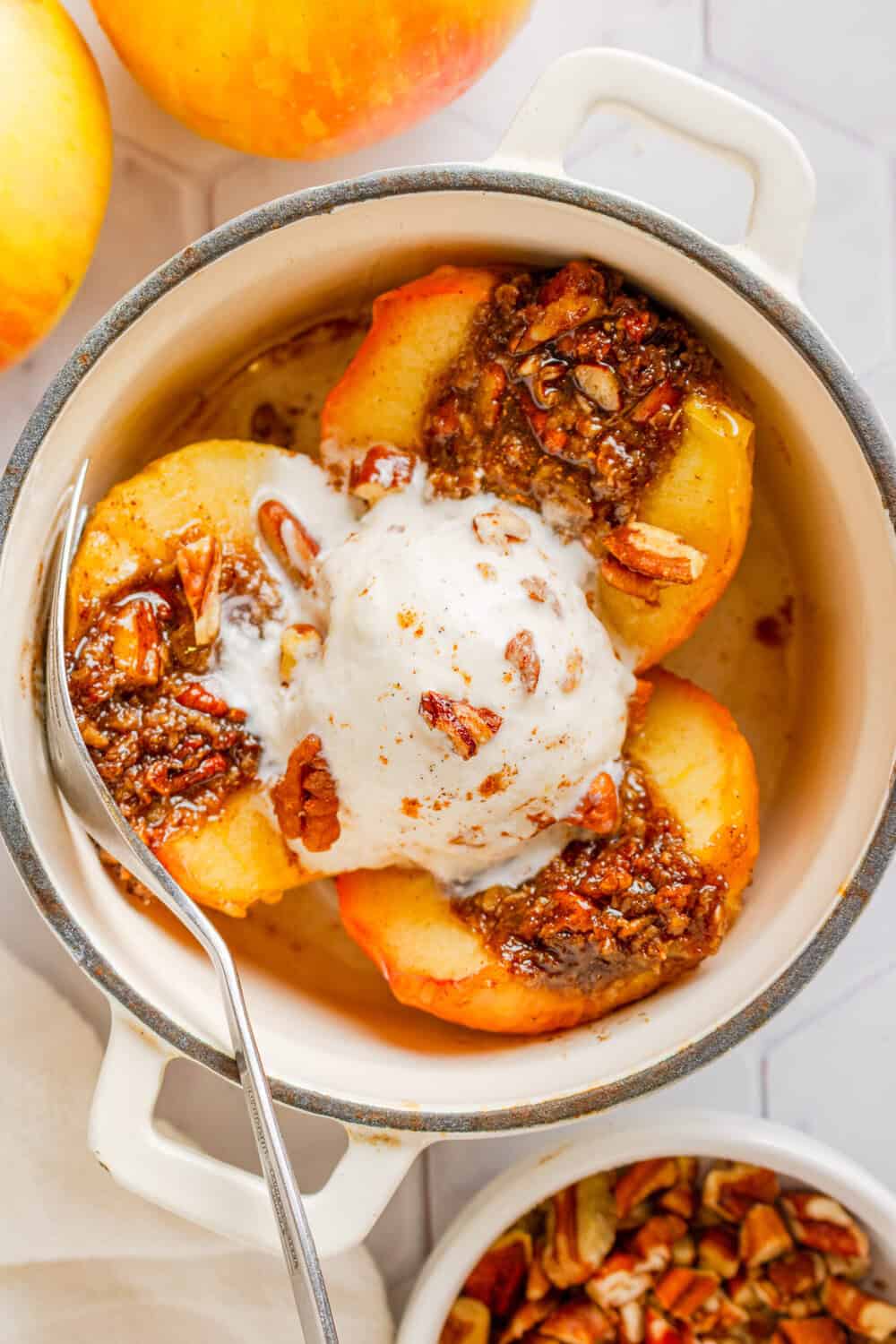 Pot filled with air fried baked apples cut in half with ice cream on top of them.