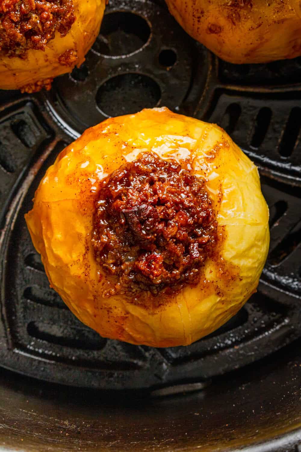Cooked sweet stuffed air fryer apples in an air fryer basket.