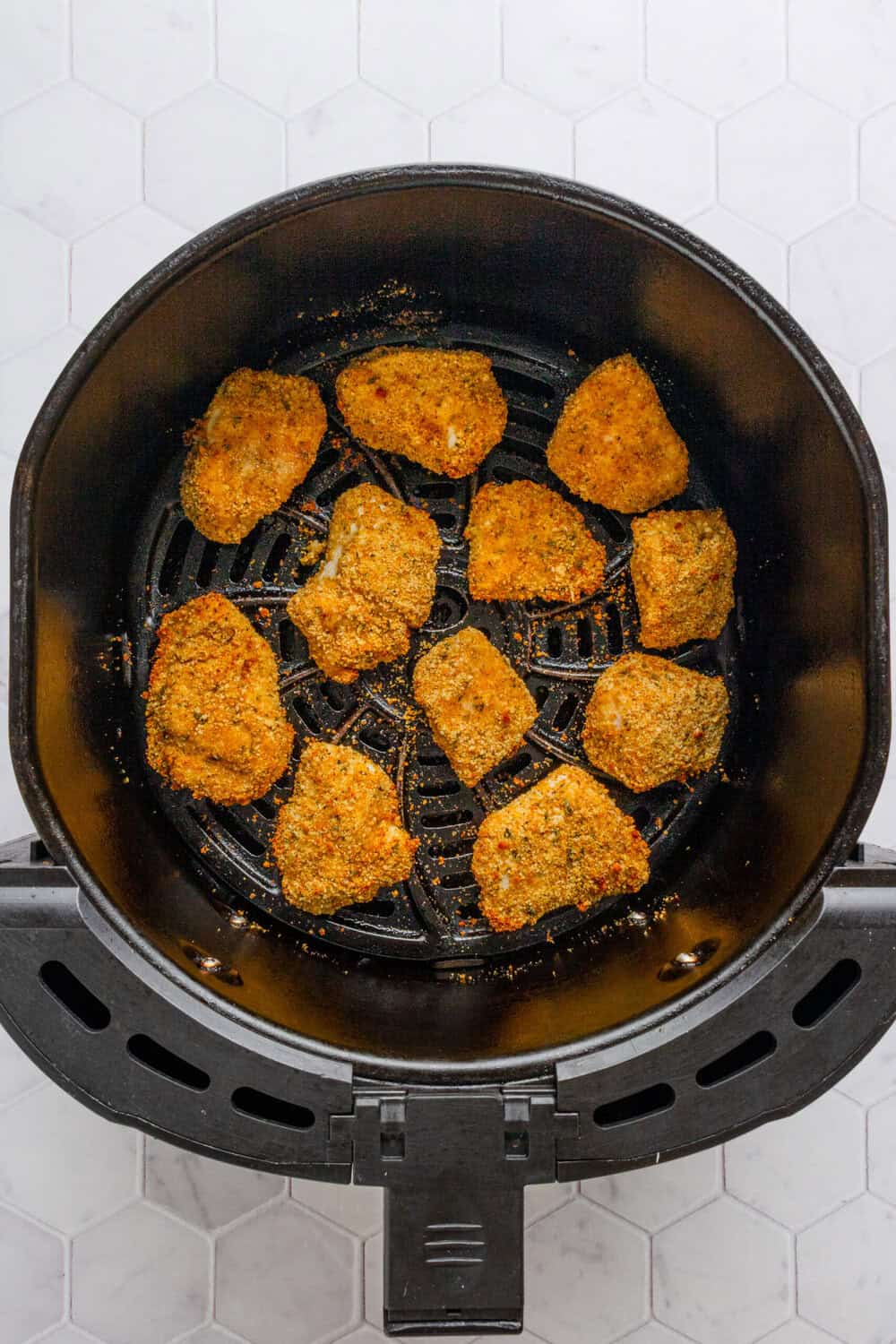 Crispy cooked homemade chicken nuggets in an air fryer basket. 