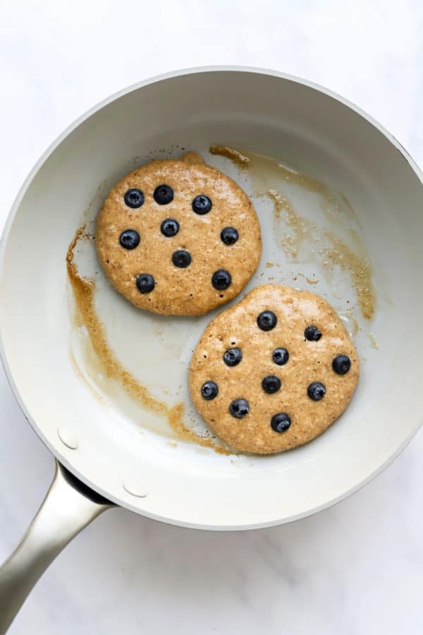 Pancakes in a grey skillet topped with blueberries