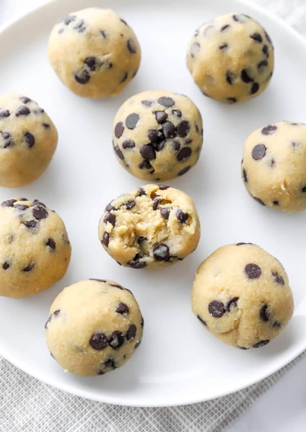 Cookie dough bites on a white plate with a bite taken out of one of them.