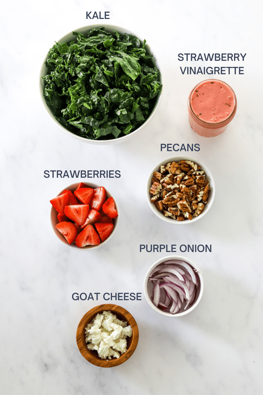 Kale and strawberry salad ingredients with labels over the top of each ingredient. 