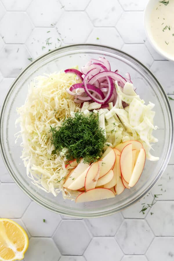 Apple fennel slaw ingredients in a round glass bowl.