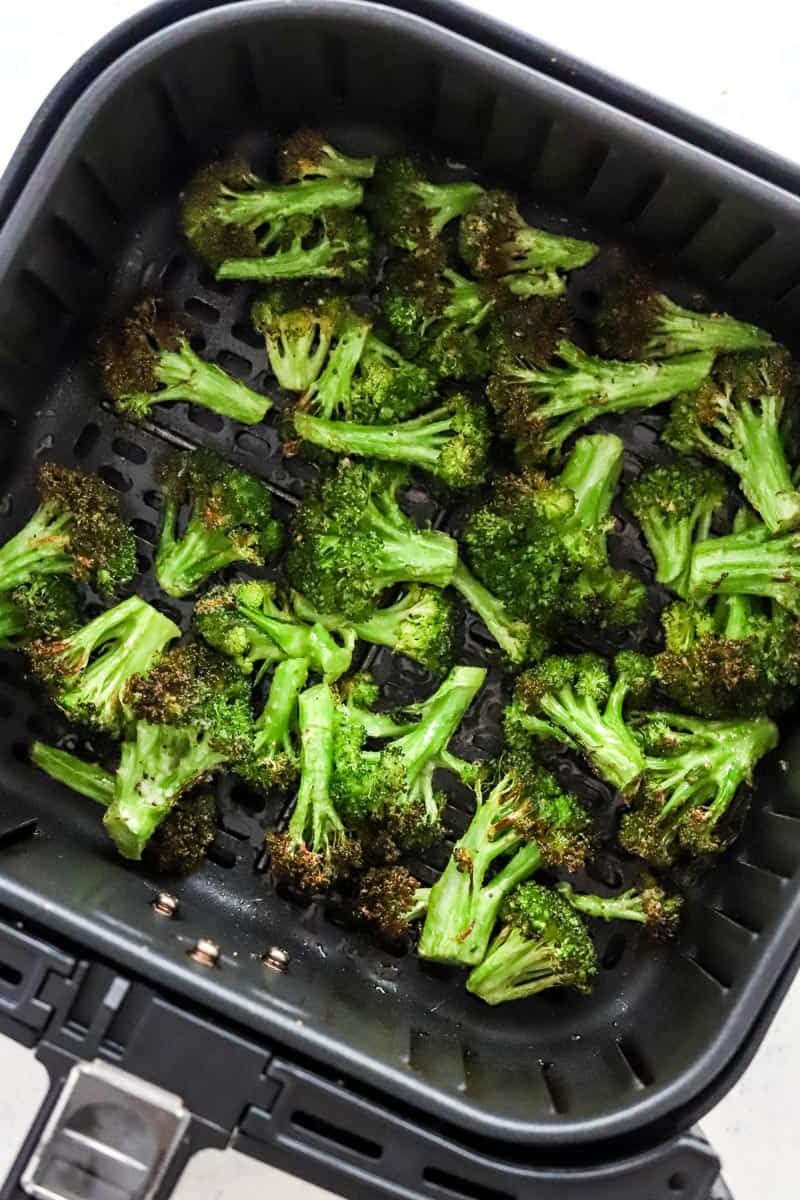 Air fryer roasted broccoli in a black air fryer basket. 