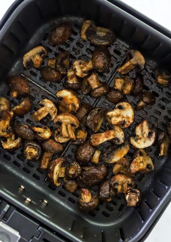 Roasted brown mushrooms in a black air fryer basket.