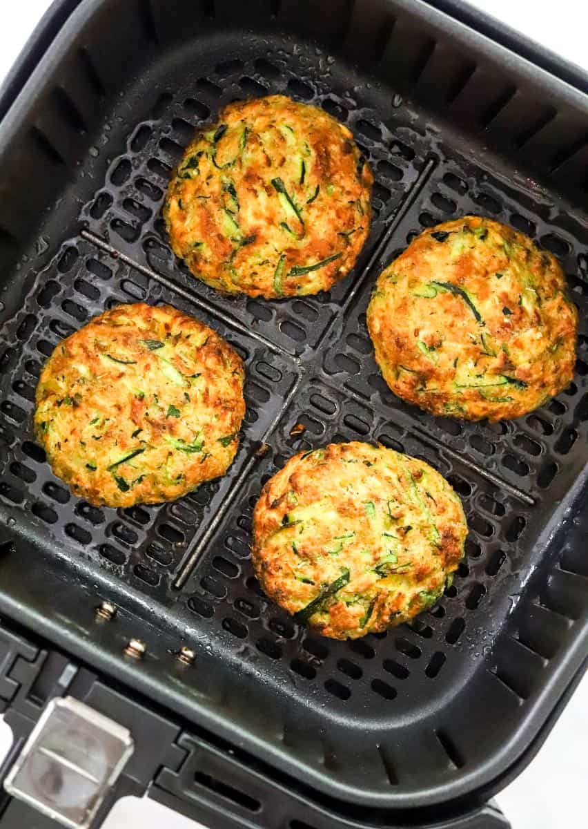 Cooked veggie patties in a black air fryer basket. 