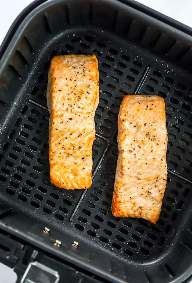Cooked salmon filets in an air fryer basket. 