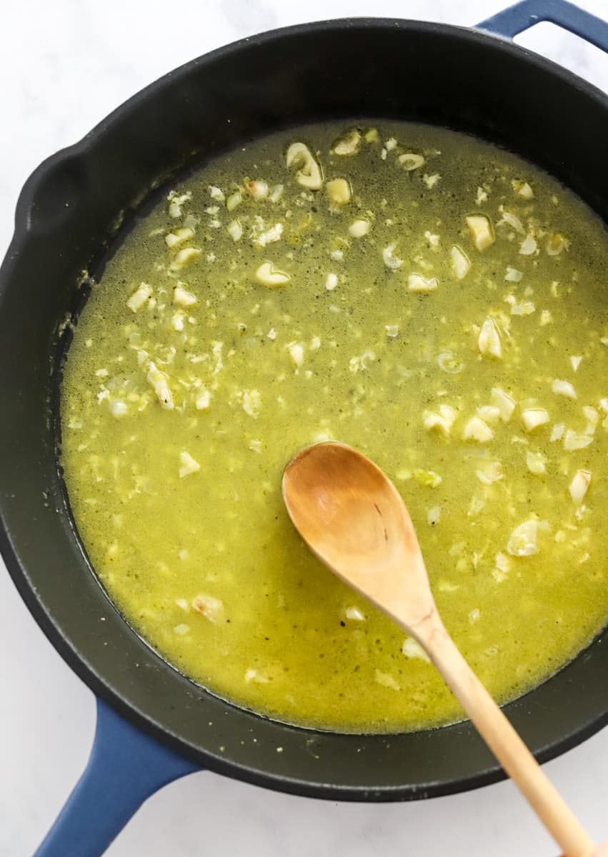 Butter sauce cooking in a cast iron pan with a wooden spoon stirring the sauce. 