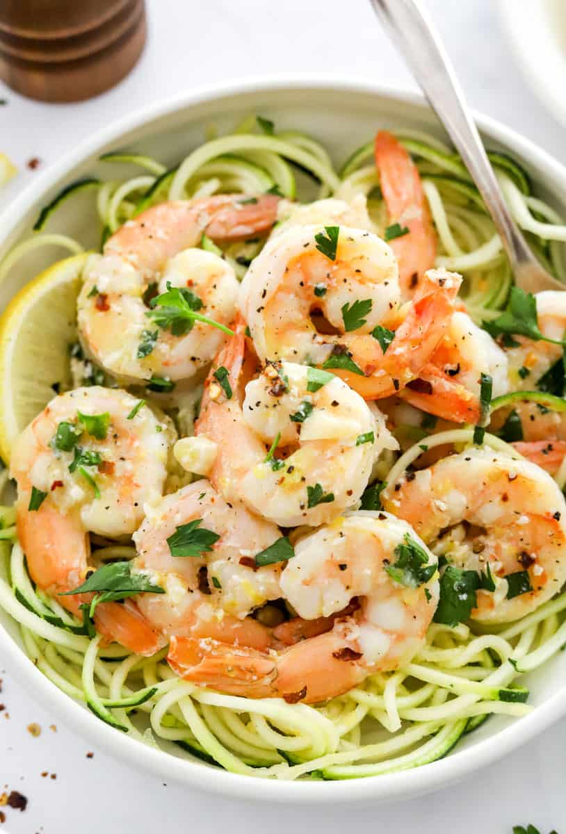Shrimp scampi over a bed of zucchini pasta with a fork in the bowl. 