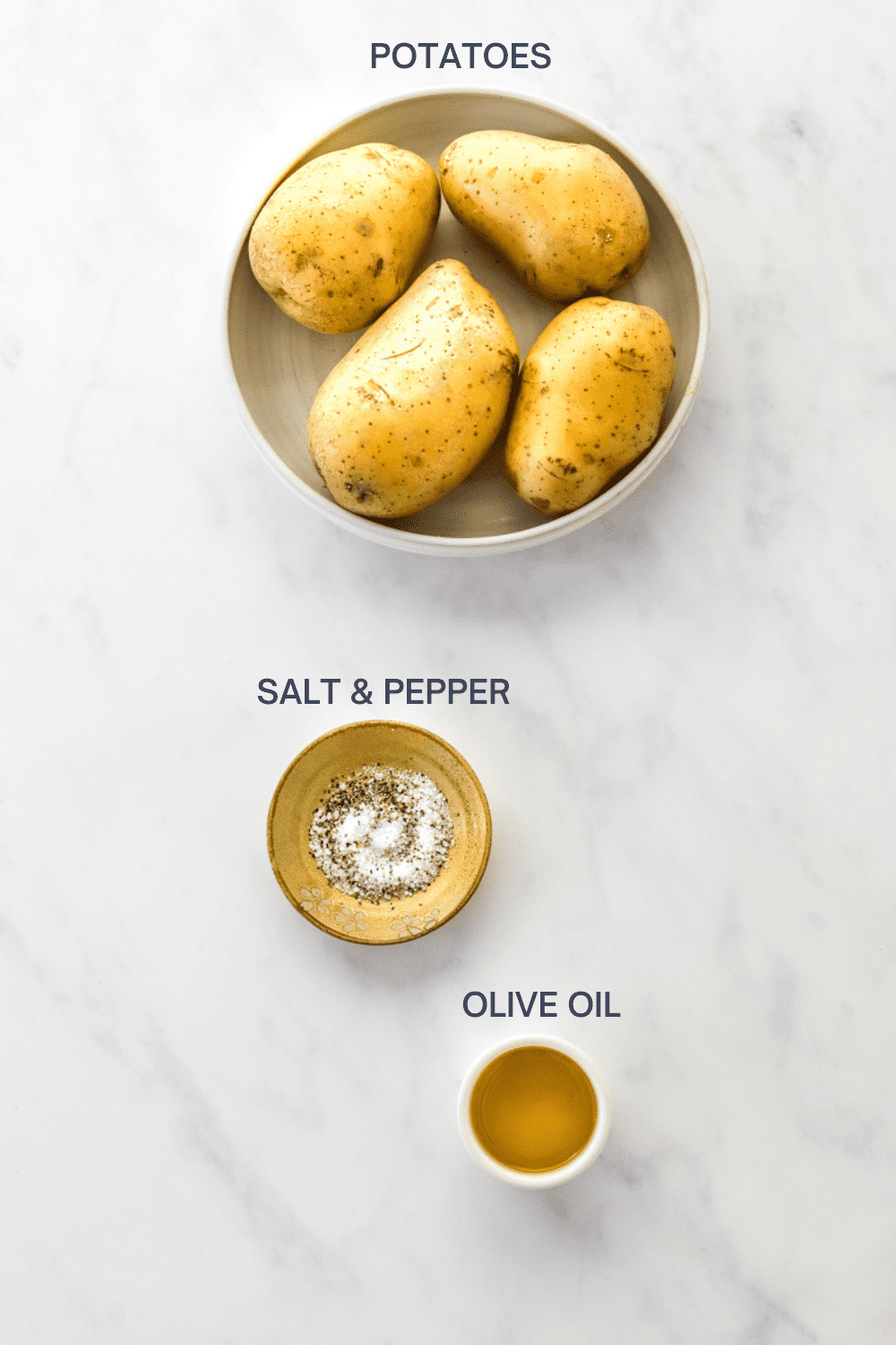 Bowl of 4 potatoes with a yellow bowl filled with salt and pepper and a small bowl filled with olive oil in front of it with labels over each ingredient.