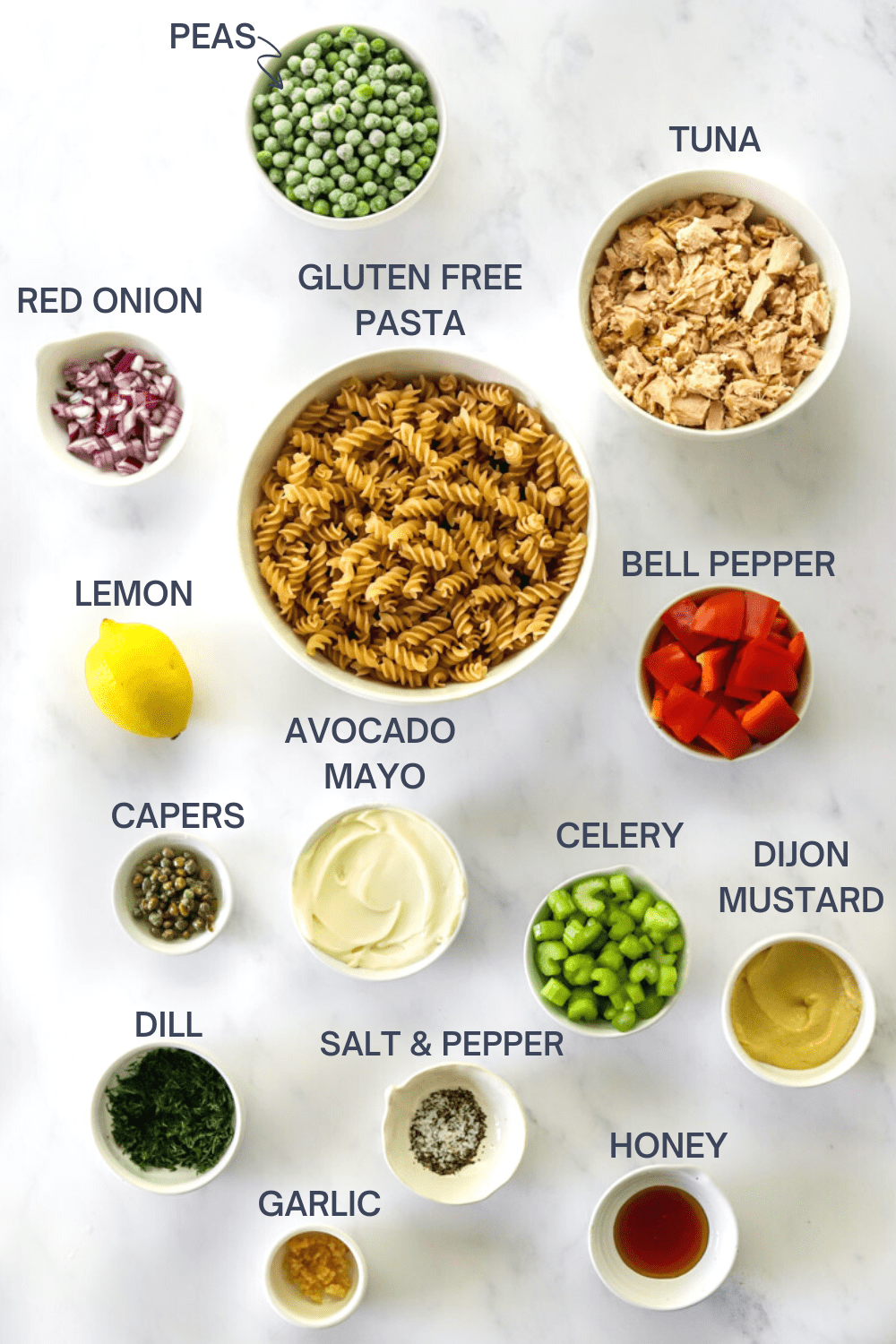 Tuna pasta salad ingredients in bowls with labels over each ingredient. 