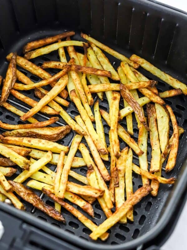 Golden cooked fries in a black air fryer basket.