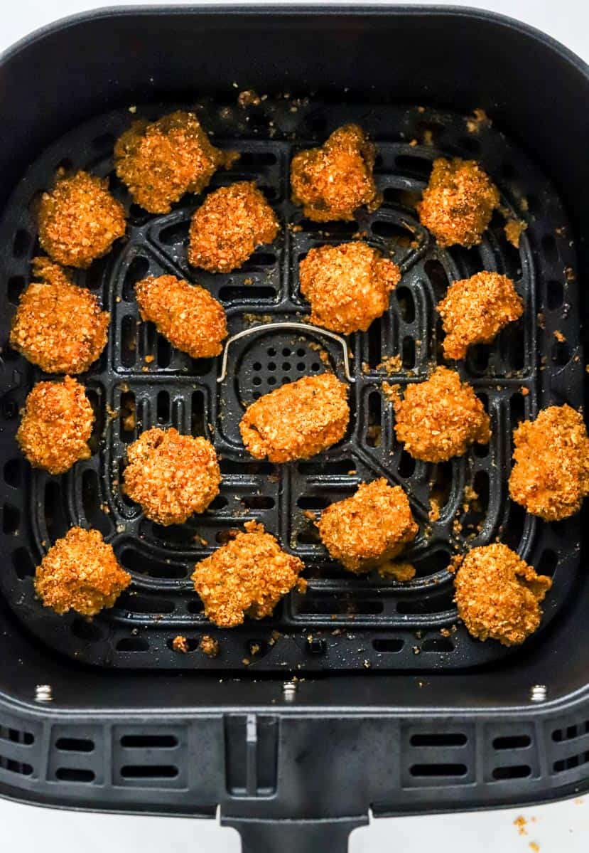 Cooked breaded chicken bites in an air fryer basket.
