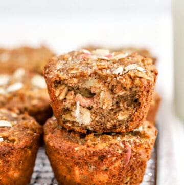 Apple grain muffins in two rows with one on top of another one with the front sliced off so you can see the inside of it.