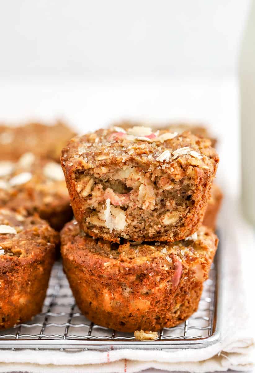 Apple grain muffins in two rows with one on top of another one with the front sliced off so you can see the inside of it.
