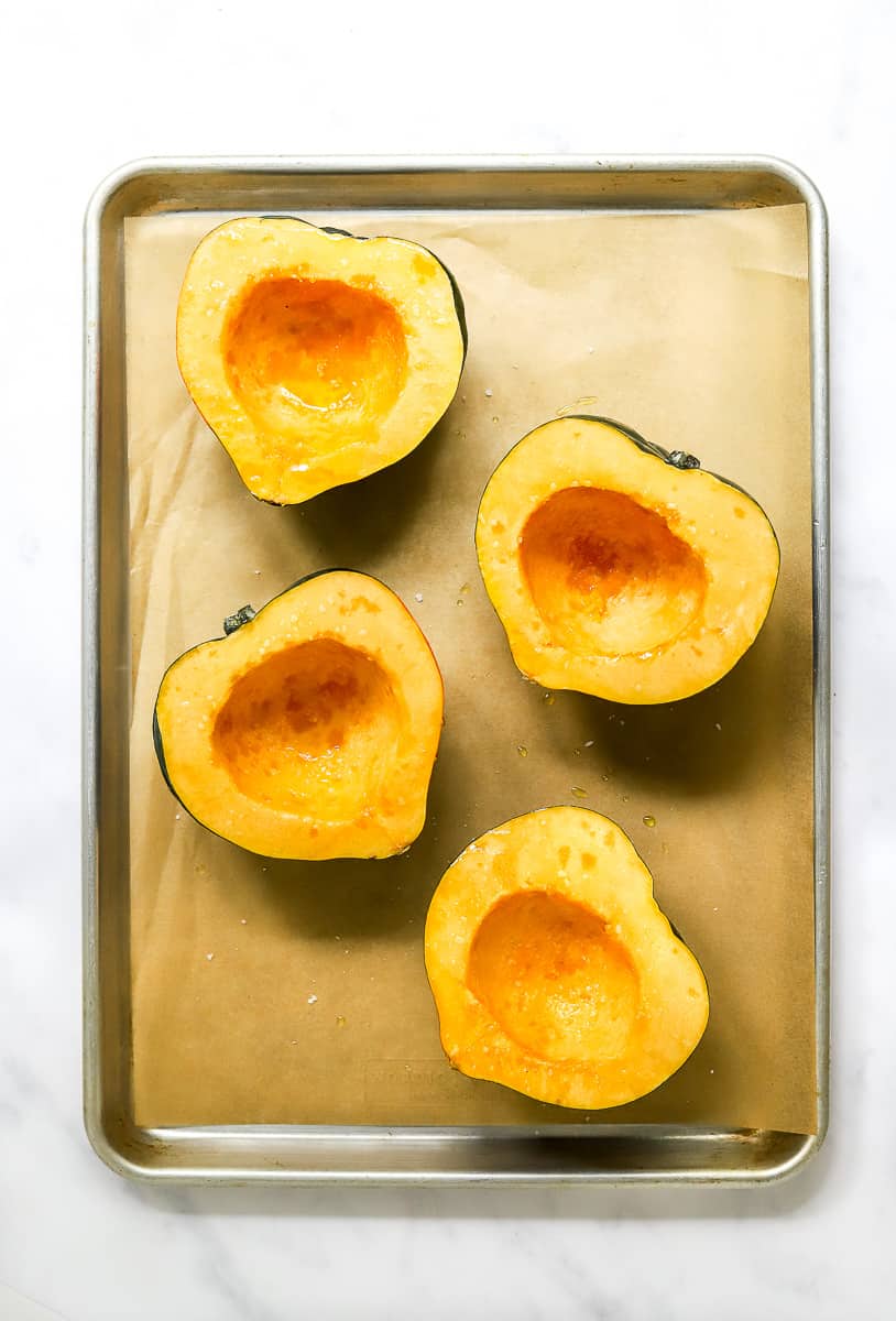 4 halves of squash on brown paper on a silver pan.