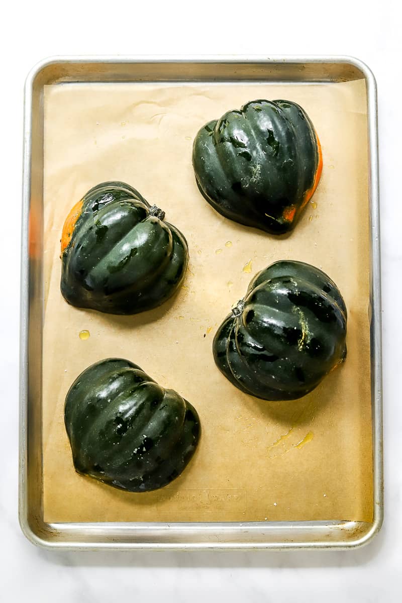Green halves of squash on a baking pan.