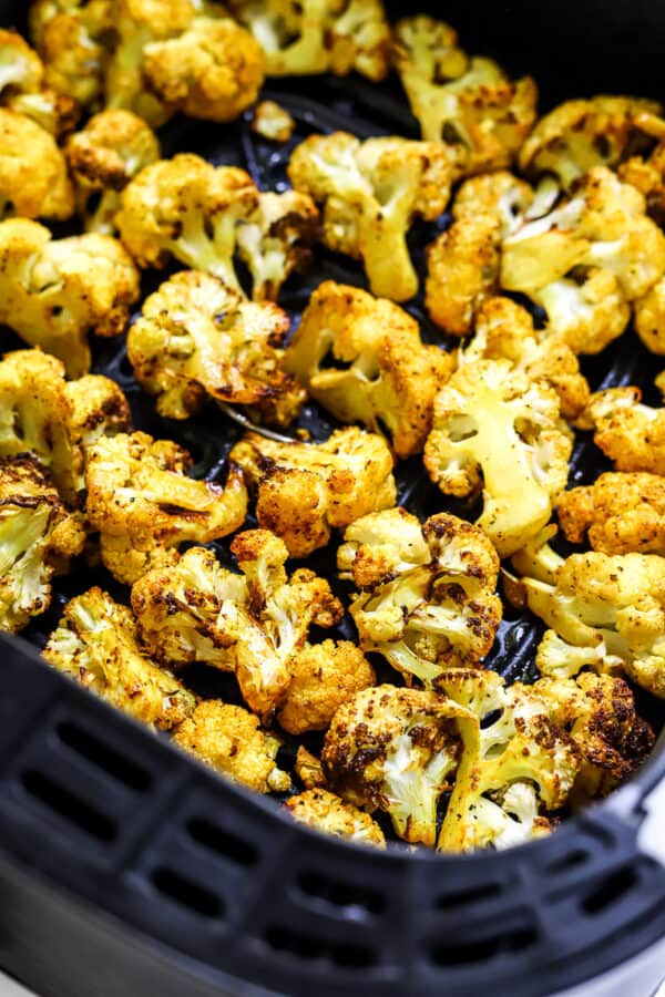 Crispy yellow cooked cauliflower florets in an air fryer.