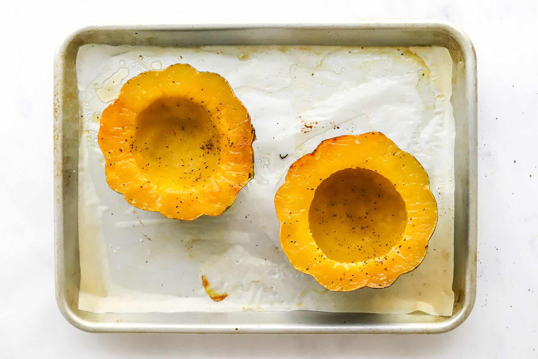 Roasted acorn squash halves on a baking sheet. 