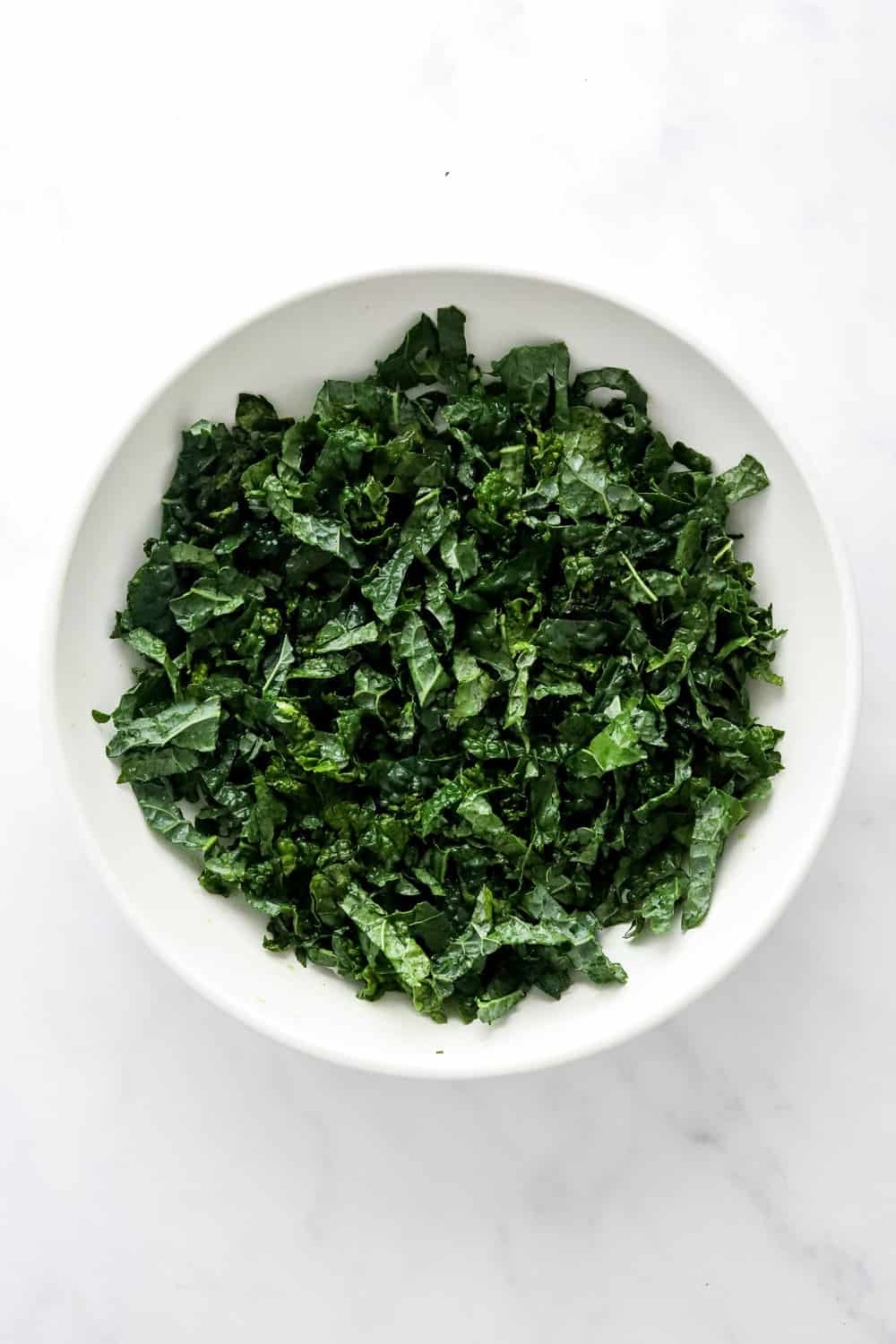 Raw, chopped kale in a white bowl.
