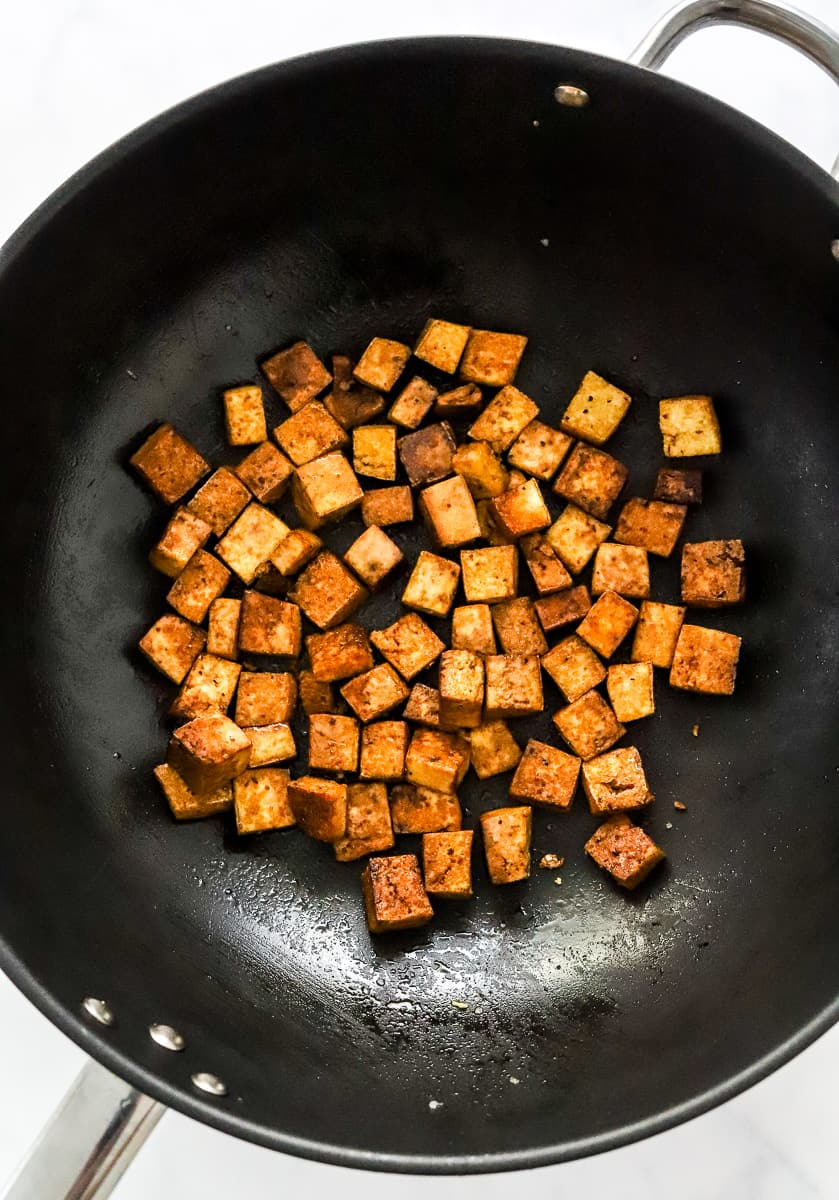 Crispy cubes of tofu in a black pan.