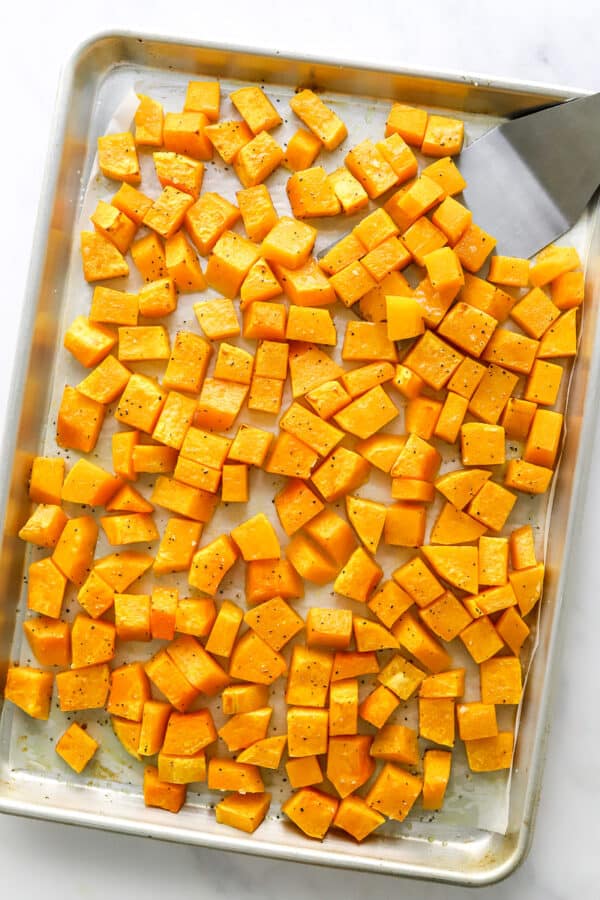 Roasted cubed butternut squash on a baking sheet.