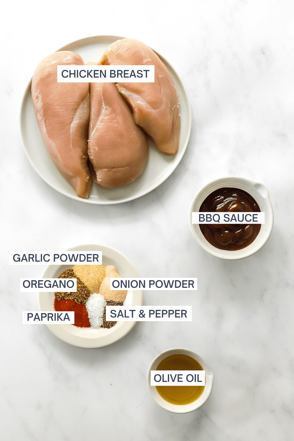 3 raw chicken breasts on a plate with a bowl of bbq sauce, a plate of spices and a small bowl of olive oil in front of it with labels for each ingredient.
