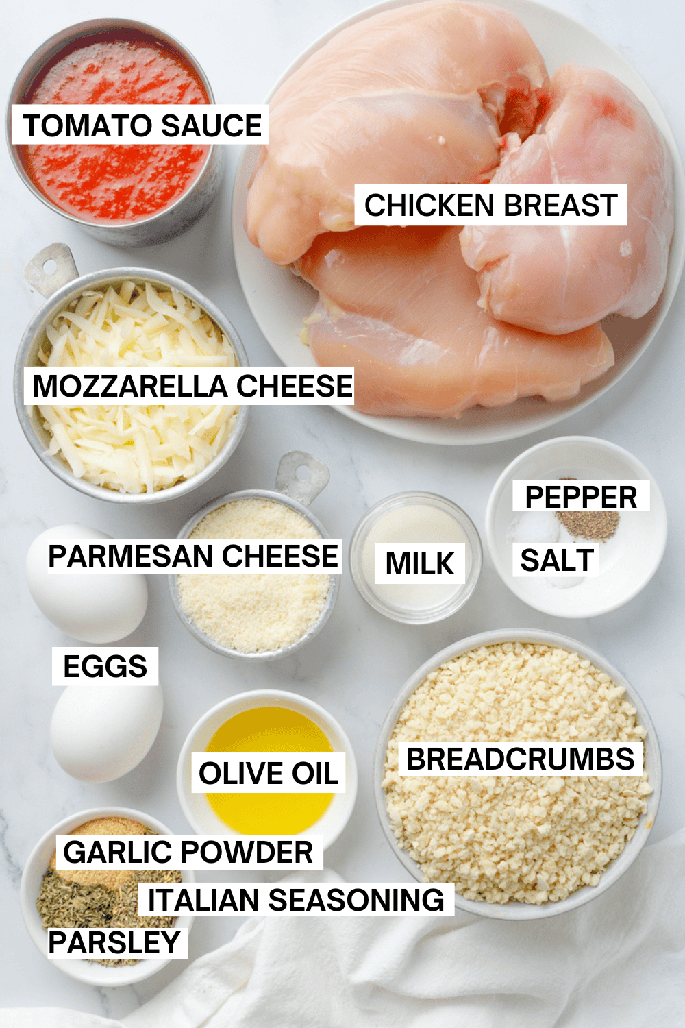 Ingredients for gluten free parmesan chicken in bowls with labels over each ingredient. 