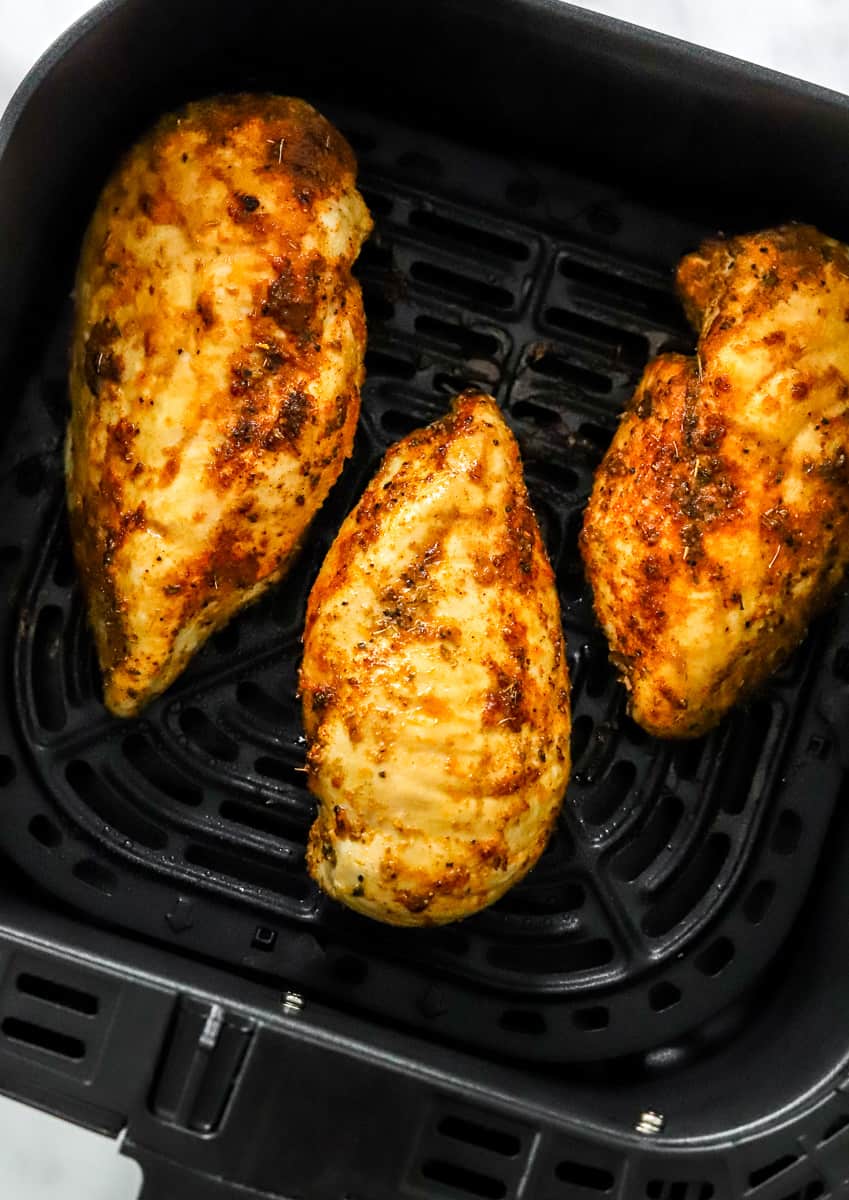3 cooked, seasoned chicken breasts in an air Freyr basket.