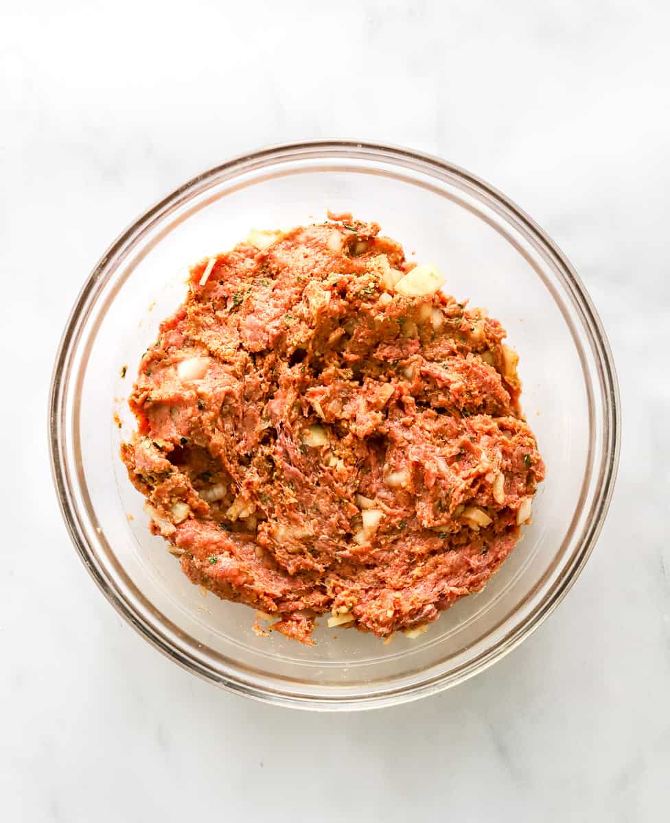 Mixed, raw meatloaf mixture in a glass bowl.